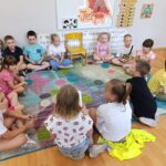 Odwiedziny uczniów ze szkoły podstawowej nr 4 w Lublińcu. Dzieci siedzą w kółku na podłodze i czytają książkę