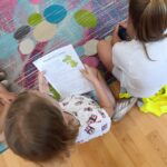 Odwiedziny uczniów ze szkoły podstawowej nr 4 w Lublińcu. Dzieci siedzą w kółku na podłodze i czytają książkę