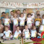 Zdjęcie grupowe dzieci z grupy Misiów w raz z ich opiekunką - dzieci trzymają w rękach pamiątkowe dyplomy