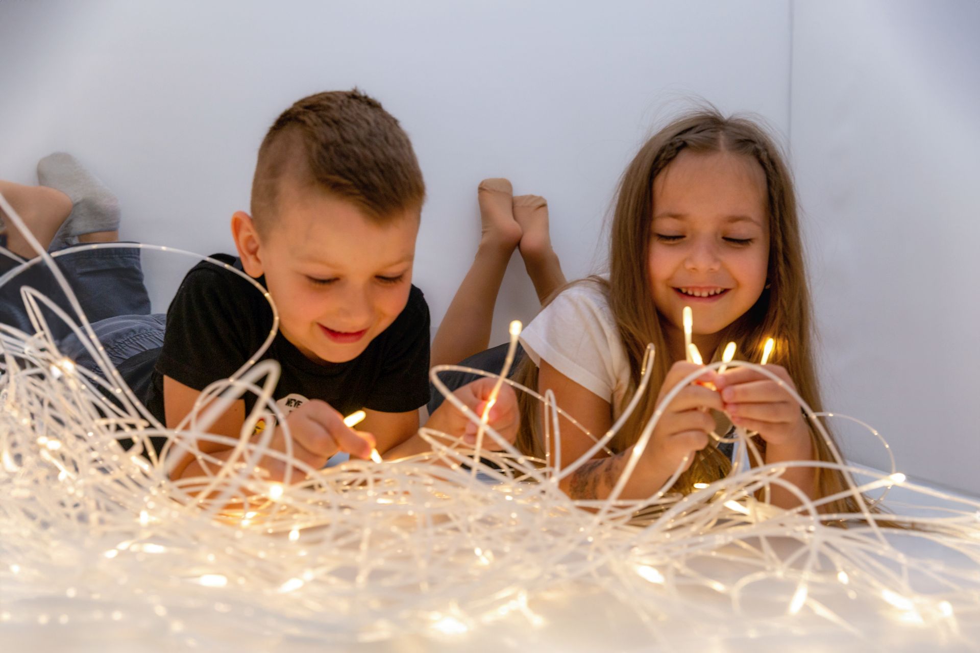 Dziewczyna i chłopiec z świecącymi lampkami o białej, ciepłej barwie