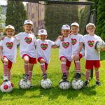 Piłkarska drużyna Przedszkola - szercioro chłopaków w sportowych, biało-czerwonych strojach z logo Przedszkola na koszulce